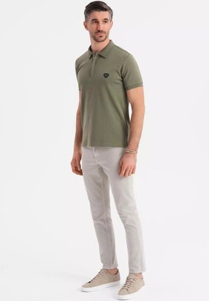 Olivengrøn polo med korte ærmer og klassisk krave, parret med lysegrå slim-fit bukser og beige sneakers.
