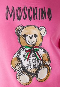 Croquis d'un ours en peluche avec un nœud papillon rouge, blanc et vert et le texte « HARD FOR FUN » sur sa chemise, au-dessus de « MOSCHINO » en lettres noires sur fond rose.