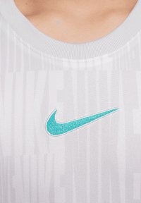 Tank top deportivo blanco de Nike, con un cuello acanalado, tejido suave y un logo bordado en color teal en el pecho.