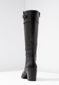 Las botas de cuero negro hasta la rodilla presentan una punta redondeada, textura suave, un zipper lateral y un tacón resistente apilado con acentos decorativos.
