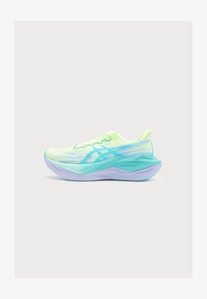 Chaussure de course vert clair et turquoise avec une semelle épaisse et anguleuse et un design à lacets sur fond gris clair uni.