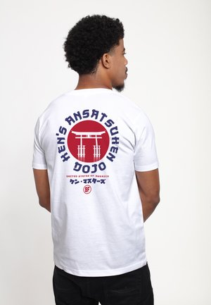 Hvid bomulds t-shirt med et cirkulært rødt design på ryggen, der har et grafisk motiv af en japansk torii-port, fed navy-tekst og yderligere detaljer nedenfor.