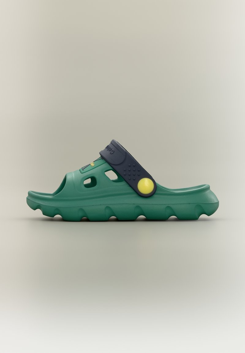 Πράσινο σανδάλι τύπου slip-on με βαθιά υφή στην σόλα, ρυθμιζόμενο μπλε λουράκι και κίτρινο κυκλικό κουμπί, εμφανίζεται σε προφίλ σε ουδέτερο φόντο.