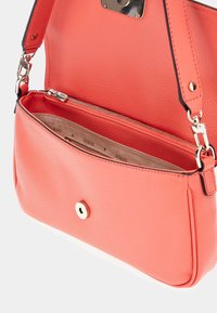 Borsa sintetica corallo con texture a conci, chiusura con zip e hardware dorato, dotata di un compartimento interno e fodera con logo.