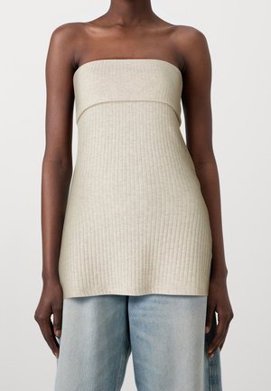 Top sans épaules en ribbed beige avec un corsage ajusté et un ourlet droit. Le tissu a une texture lisse, se mariant bien avec un jean en denim bleu clair.