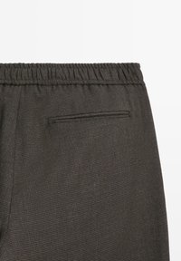 Pantaloni grigio scuro in tessuto strutturato, con vita elastica e una singola tasca sul retro con apertura nascosta.