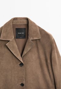 Braune Wildlederjacke mit einem Kragen, einer einzigen Reihe schwarzer Knöpfe und einem glatten Innenfutter. Das Etikett trägt die Aufschrift "Massimo Dutti".
