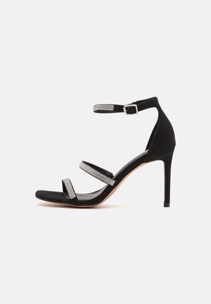 Schwarze High-Heel-Sandale mit drei rhinsteinbesetzten Riemen und einem Knöchelriemen mit silberner Schnalle.