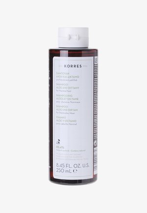 Bottiglia di shampoo in plastica marrone, con un tappo bianco. L'etichetta presenta un testo multilingue, elencando gli ingredienti e le modalità d'uso per capelli normali.