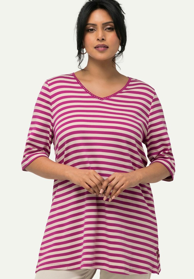 Túnica de rayas en rosa y crema, con escote en V y mangas tres cuartos, que presenta un bordado decorativo en el cuello. Tejido suave con corte relajado.