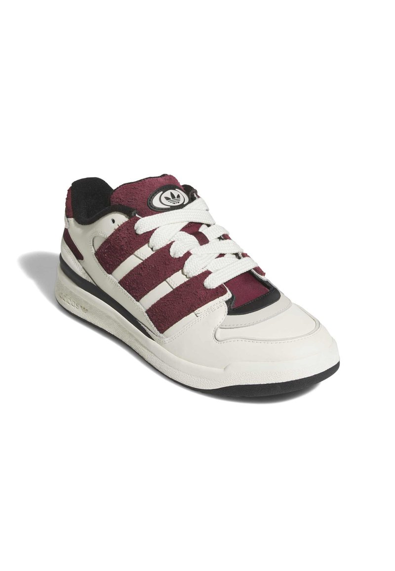 Baskets blanches avec des panneaux en daim bordeaux, comprenant trois rayures blanches, un logo rond et des accents noirs. Semelle texturée et lacets plats.