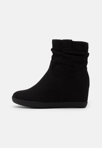 Bottines noires à talon en forme de coin avec une texture en daim doux, un design rassemblé et un bout arrondi, présentant une semelle noire texturée et sans éléments métalliques visibles.