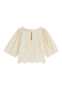 Blouse couleur crème avec des manches courtes bouffantes, un ourlet festonné, une broderie florale et une fermeture à boutons dans le cou à l'arrière.