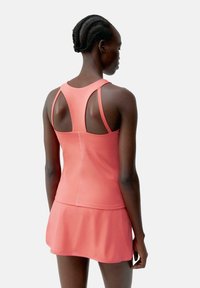 Rosa idretts tank topp med en flare skjørt. Har utskårne stropper, glatt tekstur og en tettsittende design, egnet for aktivt bruk.