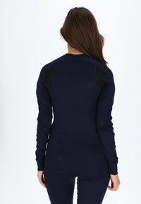 Marineblauwe thermoshirt met lange mouwen, uitgevoerd met een geribbeld textuur en zwarte mesh accenten op de schouders. Ontworpen voor een getailleerde pasvorm.