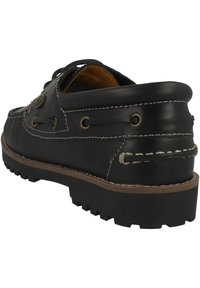 Zapato de barco de cuero negro con costuras texturizadas, punta redonda, suela de goma y ojales de metal. Presenta un tacón bajo y detalle de hilo en contraste.