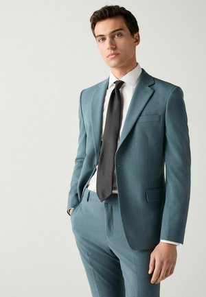 Light blue tailored suit made of smooth fabric, featuring a notch lapel, two buttons, and a black tie, paired with a white dress shirt.