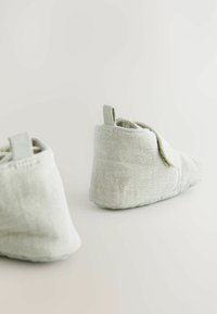 Barns mjuka, ljusgröna tygtofflor med en strukturerad yta och rund tå. Har en liten hälla för enkel påtagning.