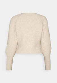 Krämfärgad kortärmad tröja i strukturerad ribbstickning, med långa ärmar och rund halsringning. Enkel och figurnära design.