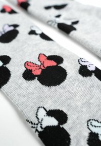 Calzini grigi con un motivo ripetuto di teste di topo nere con fiocchi di vari colori: rosa, azzurro chiaro e bianco. Texture morbida a maglia.