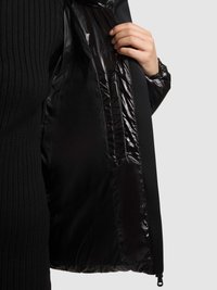 Sort dunjakke med en skinnende, quiltet foring og ribbet tekstur på ydersiden; delvist glidet op for at vise foringsdetaljerne.