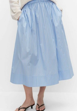 Nainen, joka käyttää sinivalkoraidallista midihameetta, jossa on joustava vyötärö ja valkoinen neule, yhdistettynä mustiin korkokenkäsandaaleihin.