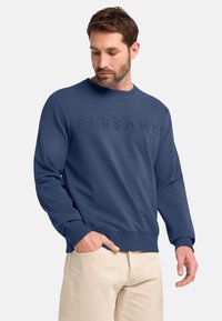 Navyblaues Sweatshirt mit geprägtem "ELBSAND"-Schriftzug. Verfügt über einen klassischen Rundhalsausschnitt und gerippte Bündchen, hergestellt aus weichem, strukturiertem Stoff.