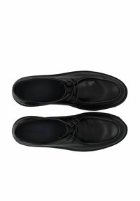 Chaussures en cuir noir avec un bout arrondi, un laçage et des coutures visibles sur le bord. Texture lisse avec un style minimal.