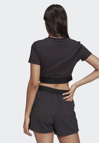 Avskuren svart t-shirt med korta ärmar, ihop med svarta shorts med elastisk midja och bakficka. Mjuk tygtextur.