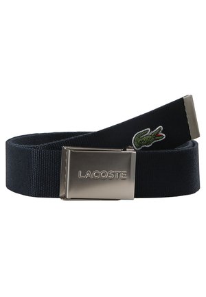 Navy fabric belt with a metal buckle featuring the "LACOSTE" logo. Includes a green embroidered crocodile detail. Textured surface.