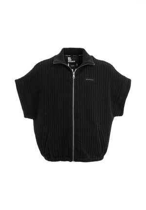 Chaqueta negra acolchada de manga corta con cremallera, cuello alto y dos bolsillos delanteros, dobladillo elástico y pequeño detalle de parche en el pecho.