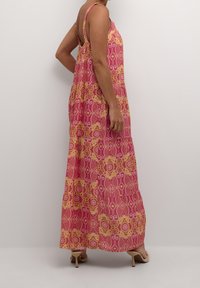 Maxi dress features a pink and yellow floral pattern, sleeveless design, flowing fabric, and a loose fit with pleated detailing.