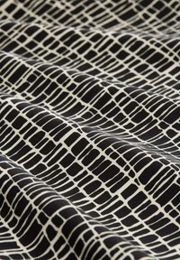 Textil mit einem schwarz-weißen Muster aus unregelmäßigen rechteckigen Formen, mit einer glatten, matten Textur und einem fließenden, drapierenden Erscheinungsbild.