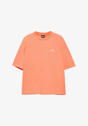 Kirkkaan oranssi lyhythihainen pyöreäkauluksinen t-paita, jossa pieni valkoinen logo vasemmassa rinnassa, valkoisella taustalla.