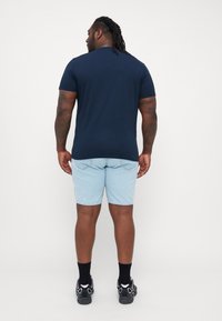 Tume sinine lühikeste varrukatega T-särk, helesinised denim-lühikesed püksid, mustad sokid ja mustad kingad. Omab lihtsat disaini ja vabalt langevat lõiget.