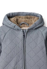Granatowa pikowana kurtka z kapturem z ukośnymi białymi paskami. Podszyta beżowym polarem, z przednim zamkiem błyskawicznym i pętelką do zawieszania.