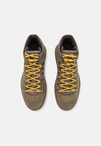 Botas de senderismo de ante marrón con cordones amarillos, ganchos de metal y soporte acolchado para el tobillo. Diseñadas para la durabilidad y actividades al aire libre.