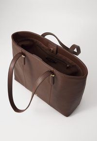 Brun læder tote taske med to håndtag, guldfarvede detaljer, åbent top og indvendig lomme til opbevaring. Glat tekstur og enkelt design.