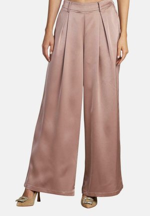 Pantalones de pierna ancha hechos de una suave tela rosa claro con pliegues en la parte delantera. Presentan una cintura alta y están combinados con zapatos de tacón. 
