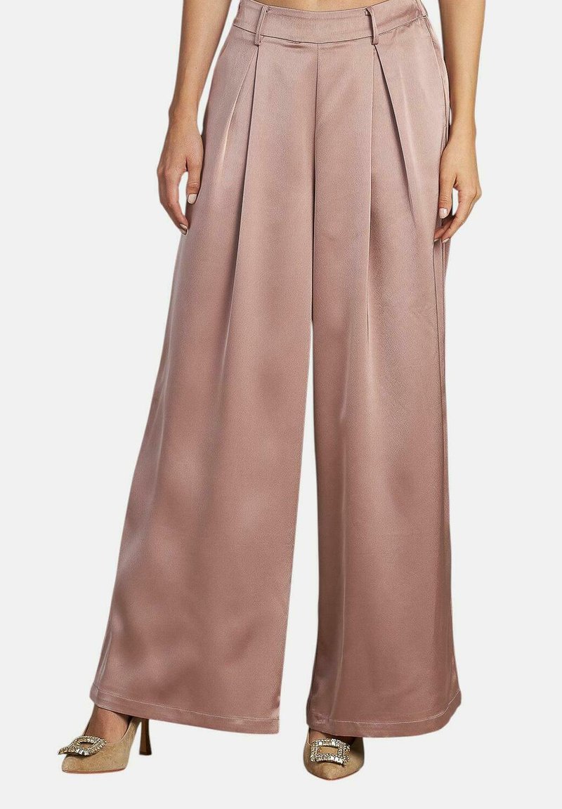 Weit geschnittene Hosen aus glattem, hellrosa Stoff mit Falten an der Vorderseite. Sie haben eine hohe Taille und sind mit Riemensandalen gestylt.