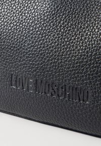 Borsa in pelle nera texturizzata con logo in rilievo "LOVE MOSCHINO". La superficie presenta un motivo leggermente in rilievo.