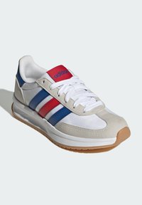 Sneaker with white nylon upper, gray suede accents, blue and red stripes, white laces, and a gum rubber sole. Notable "adidas" branding.