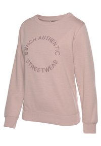 Lichtroze sweatshirt met lange mouwen, ronde hals en geribbelde manchetten. Beschikt over geborduurde tekst in een cirkelvormig patroon aan de voorkant.