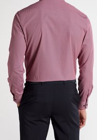 Rood patroon lang-illustratieve shirt met een button-down kraag. Kenmerkt zich door een subtiele textuur en contrasterende zwarte knopen. Draagt met donkere, op maat gemaakte broeken.