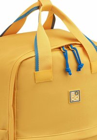 Borsa a sacca gialla con tessuto testurizzato, cinturini blu a contrasto, chiusure a doppio cordino e patch con logo, caratterizzata da una forma rettangolare.