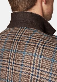 Brązowa kurtka w kratę z teksturowanej tkaniny, z ciemnobrązowym filcowym kołnierzem i niebieskimi akcentami w całym wzorze.