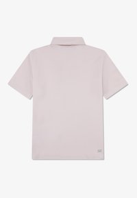 Polo shirt in light pink with short sleeves and a classic collar. Smooth cotton material with subtle branding on the lower right.