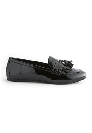 Mocassin en cuir verni noir avec décoration à pampilles sur le dessus, petit talon et semelle en caoutchouc texturée, vu de profil sur fond blanc.