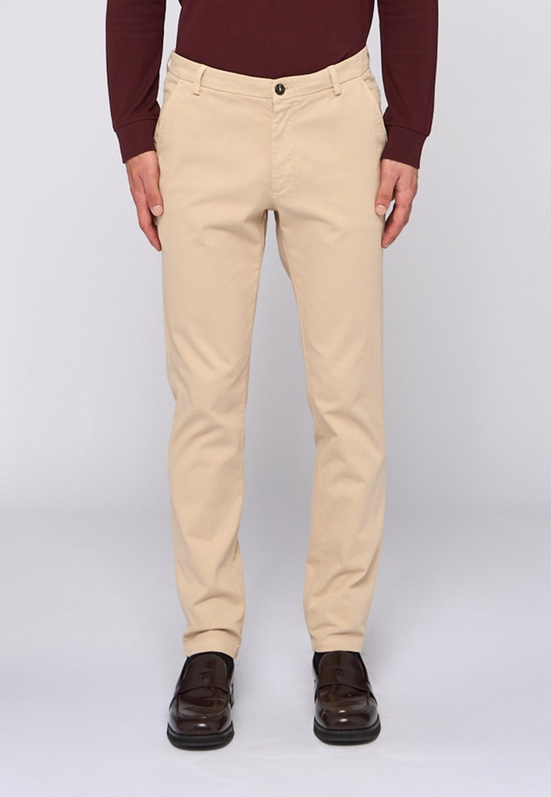 Beige Chinos in schlanker Passform, gefertigt aus leichtem Stoff. Verfügt über einen klassischen Knopfverschluss, Gürtelschlaufen und Seitentaschen.