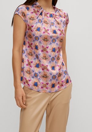 Blouse à manches courtes en tissu léger avec un motif floral rose, orange et bleu ; présente un col plissé et un ourlet arrondi.
